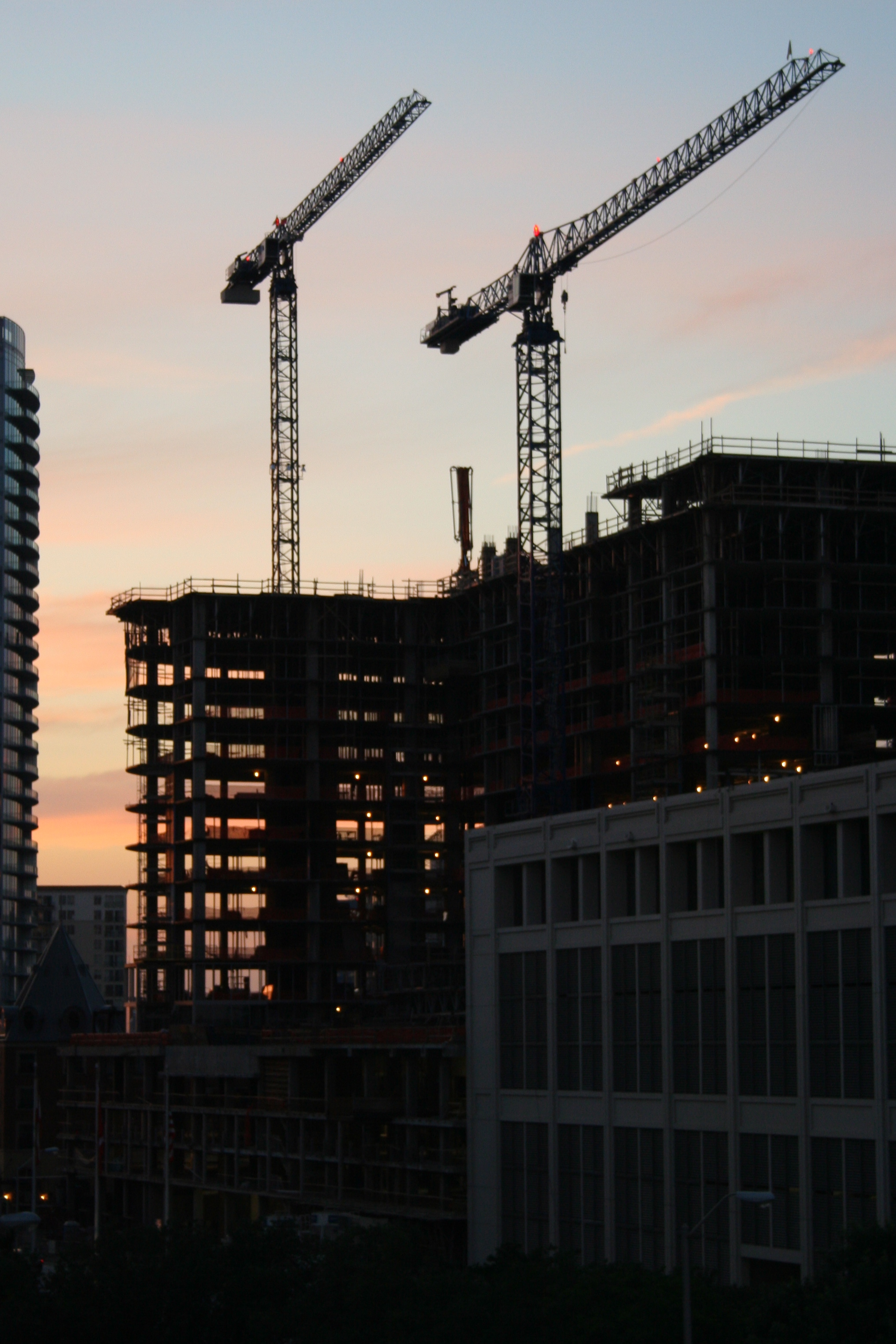Construction cranes over an urban building at dusk